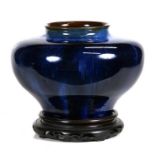A Denby blue glazed vase of compressed globular form, on an associated pierced hardwood stand, 22cms