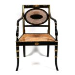 A Regency style ebonised and gilded elbow chair with caned seat & back.