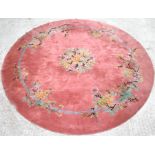 A large Chinese circular woollen rug decorated with flowers on a pink ground,