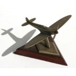 A metal model of the iconic Supermarine Spitfire mounted on a wooden base, wingspan of 10cms (