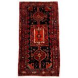 A Kurdish hand knotted Kordi runner with geometric medallions on a red ground, 325 by 150cms (128 by