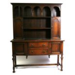 An oak dresser with plate rack flanked by two cupboards, the base with two long drawers flanked by