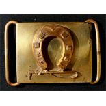 A brass horse riding themed belt buckle with a horseshoe and carriage whip to the front. Overall