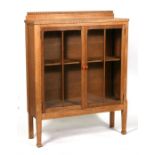 An early 20th century oak glazed bookcase with shilved interior standing on square tapering legs.