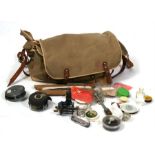 A canvas fishing bag containing fly fishing reels, fishing priest; and other items.