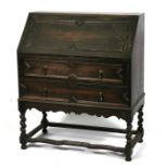 An early 20th century oak bureau with geometric moulding, the fall flap enclosing a sectioned