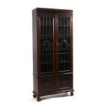 An early 20th century stained walnut glazed bookcase, the two leaded glass doors enclosing a shelved