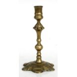 An early 18th century brass seamed candlestick, 23cms (9ins) high.