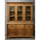 A modern handcrafted pine dresser, the glazed upper section enclosing a shelved interior, with three