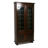 An oak bookcase, the pair of leaded glass doors enclosing a shelved interior, with cupboard beneath,