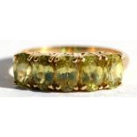 A 9ct gold dress ring set with five oval pale green stones, approx UK size 'N'.