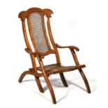 An Edwardian satin birch steamer chair with caned seat and back.
