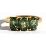 A 9ct gold dress ring set with three oval pale green stones, approx UK size 'N'.