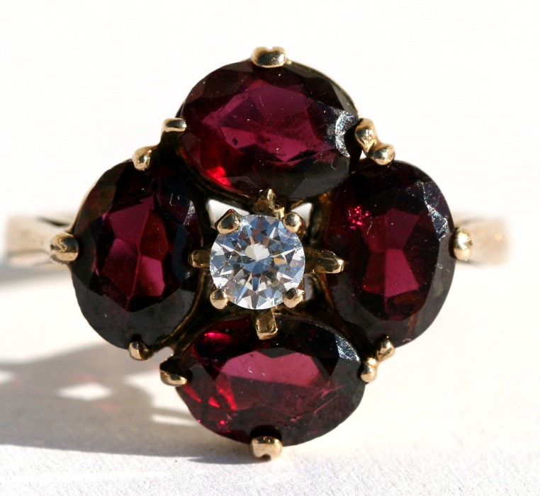 An Edwardian style 9ct gold dress ring set with four garnets and a central white stone, approx UK