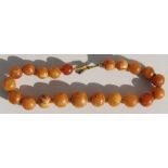 A butterscotch amber necklace with twenty one graduated round natural beads with good egg yolk
