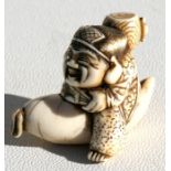 A 19th century Japanese Meiji period ivory netsuke of Daikoku holding a fan and a mallet seated on a