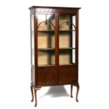 An Edwardian mahogany display cabinet, the pair of glazed doors enclosing a shelved interior, on