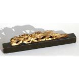 A Chinese gilded lacquer scroll weight in the form of a dragon, 23cms (9ins) wide.