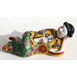 A Chinese famille rose figure depicting a recumbent lady holding a fan, 18cms (7ins) long.