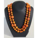 A butterscotch amber bead necklace with sixty nine round and oval beads, 126cms (49.6ins) long.