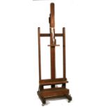 An early 20th century oak adjustable easel, the adjustable rack standing on four casters, 70cms (