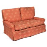 A modern two-seater sofa with coral pink upholstery.