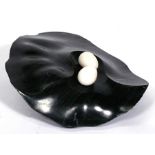 A Flinto Chandia (Zambia) marble sculpture depicting two eggs on a black nest, 69cms (27ins) wide.