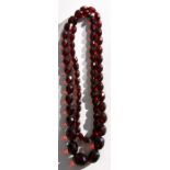 A cherry amber Bakelite necklace comprising seventy graduated faceted oval beads, the largest 18mm