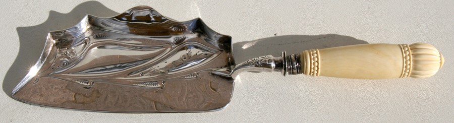An Art Nouveau silver plated crumb scoop with turned ivory handle, 33cms (13ins) long.