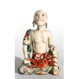 A 19th century Japanese Satsuma figure of an emaciated monk sat with a crab, 11.5cms (4.4ins) high.