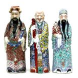 A group of three Chinese famille rose figures depicting robed men, the largest 48cms (18.75ins)