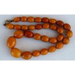 A butterscotch amber bead necklace comprising thirty one graduated oval beads, the largest 17mm (0.