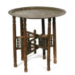 A tray top table on folding base decorated with Islamic script, 58.5cms (23ins) diameter.