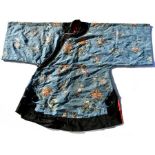 A Chinese silk embroidered short robe decorated with flowers and butterflies on a blue ground,