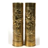 A matching pair of WW1 trench art shell case vases elaborately decorated with embossed foliage.