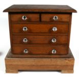 A Victorian oak miniature chest with two short and three long drawers, on associated oak base, 48cms