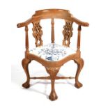 A Georgian style walnut corner chair with carved lion mask arms and pierced back splats, on acanthus