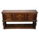 A Jacobean style oak dresser base with two central drawers flanked by cupboards, on turned &