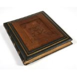 A large Victorian leather bound photograph album with ornately carved wooden front panel, containing