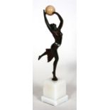 An Art Deco style bronzed figure depicting a dancing lady with a ball, mounted on a white marble