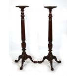 A pair of mahogany torcheres, the turned column on acanthus capped tripod legs with ball & claw