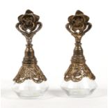 A pair of gilt metal mounted glass scent bottles with rose finials, 17cms (7ins) high.