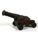 An impressive cast iron signal cannon, sitting on a wooden carriage and wheels. Barrel length