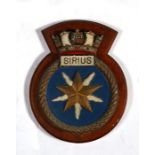 A hand painted aluminium ships crest or plaque mounted on a wooden shield to HMS Sirius. Overall