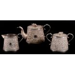 An Indian silver three-piece tea set with all over chased foliate decoration and elephant finials,
