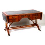A reproduction yew wood writing table with inset leather top and drop flaps above an arrangement