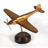 A brass model of a WW2 Supermarine Spitfire mounted on a wooden base. Wingspan 24cms (9.5ins)