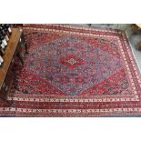 A large 20th century carpet, on a red ground, with central diamond motif and repeater boarder, 350cm