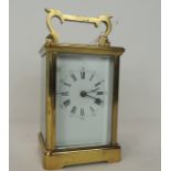 A carriage timepiece in brass case with white enamel dial 15cm high with handle raised