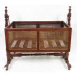 A late Victorian mahogany and woven cane swing cradle, having turned supports, original metal